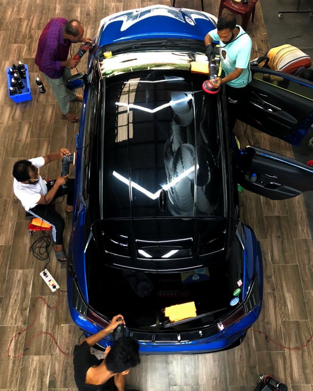 People detailing a blue car top view